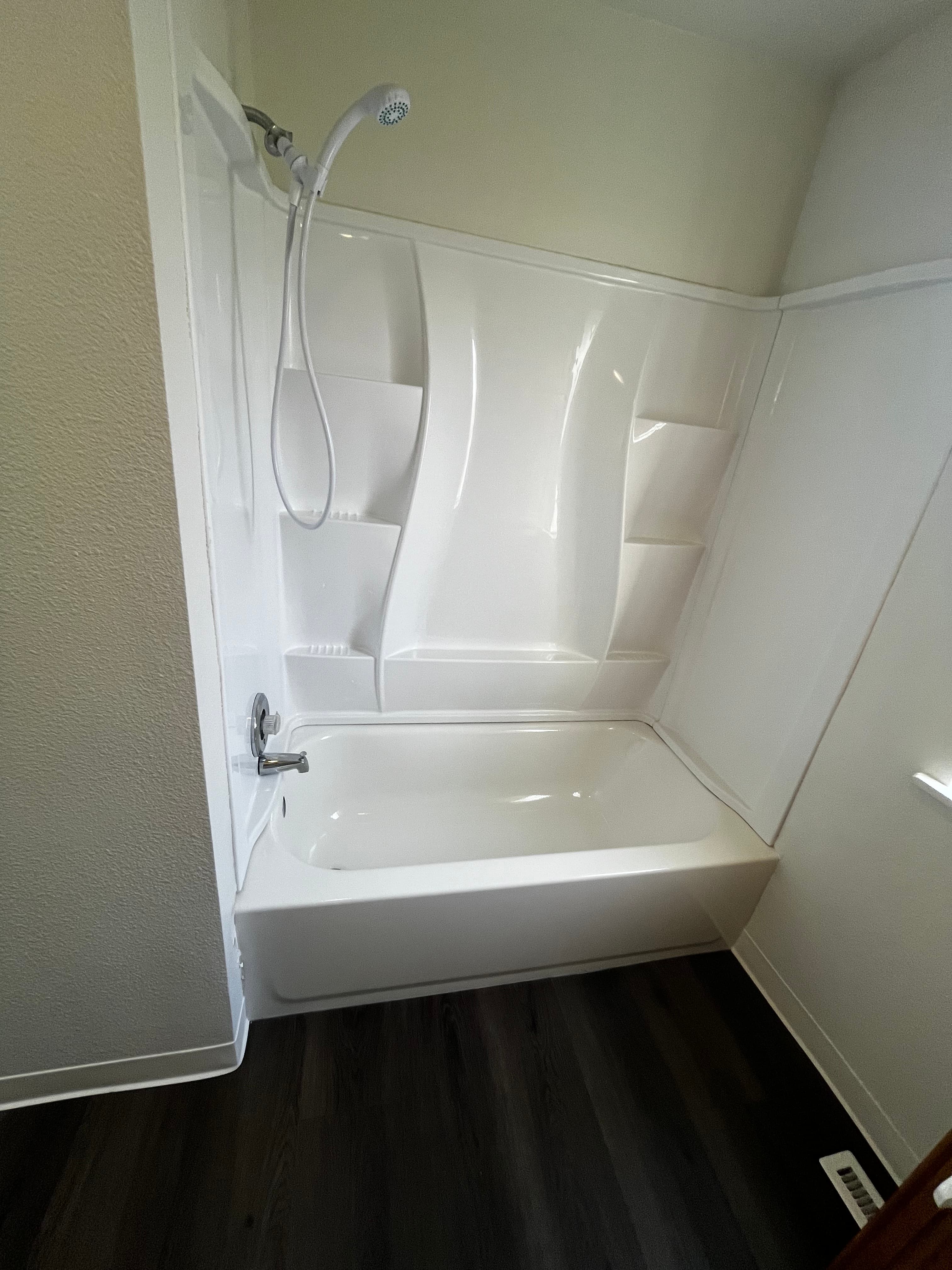 Gleaming white bathtub and shower surround after professional cleaning