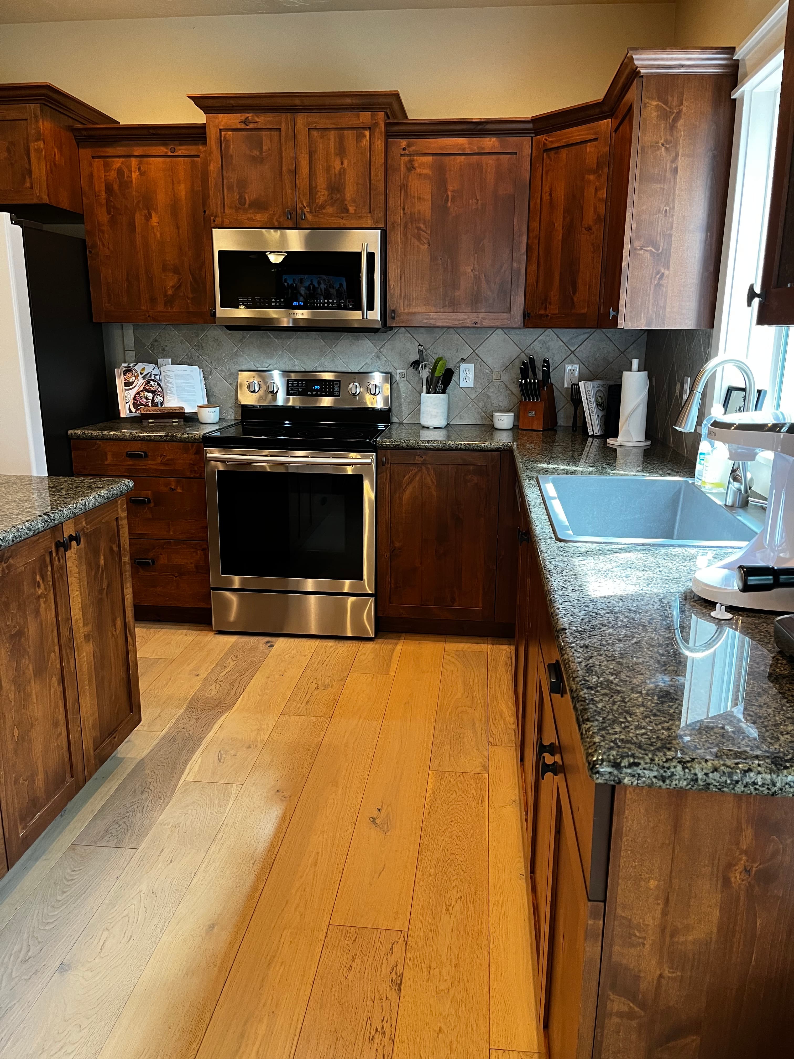 Spotless modern kitchen with polished granite and stainless appliances after a Feather & Steel clean