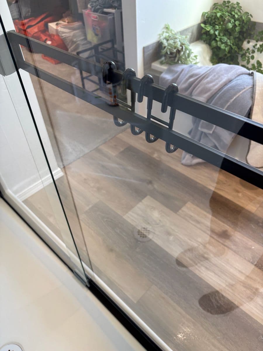 Clear sliding shower glass with black towel bar after hard-water spots were removed
